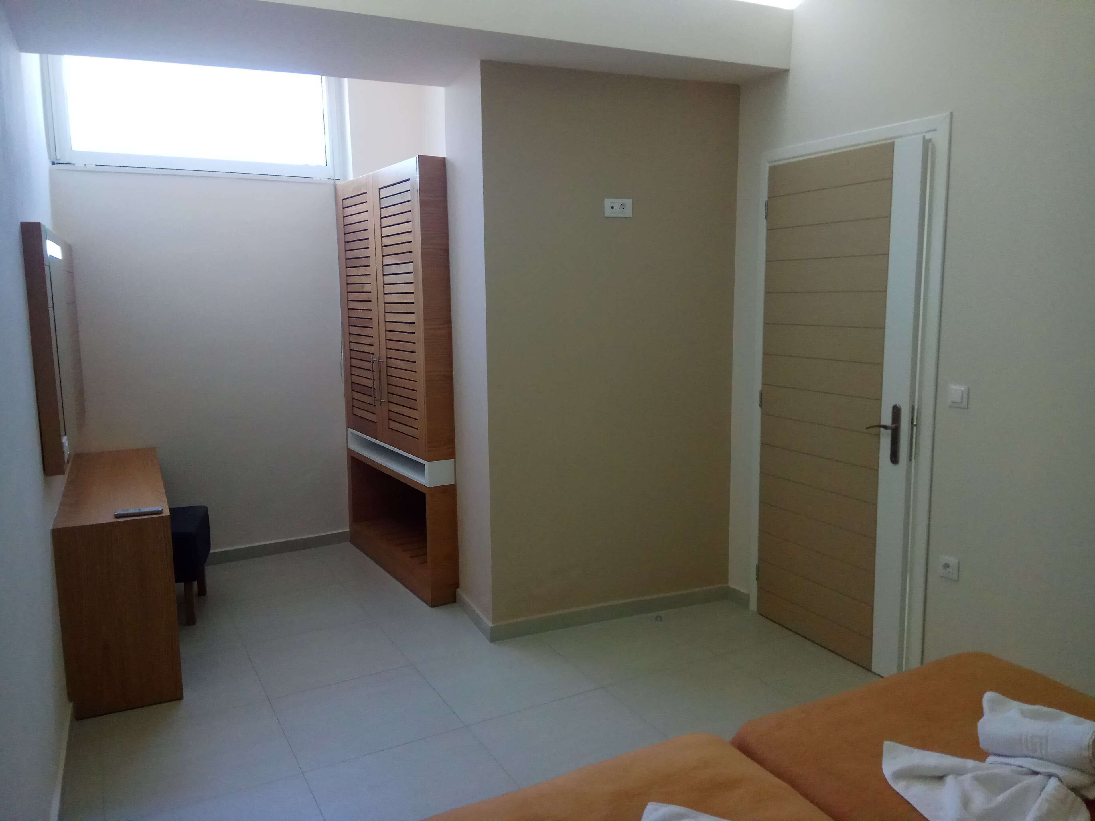 Ein Zimmer mit Bett, Kleiderschrank, Schreibtisch und Fenster.