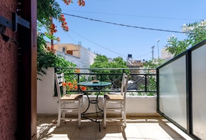 Enjoy dining or relaxing on the balcony with a table and two chairs, offering a view of the surrounding residential area.
