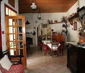 Traditional dining room with a wooden table and chairs, leading to a spacious area beyond.