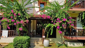A building with a covered entrance, outdoor seating, and potted plants.