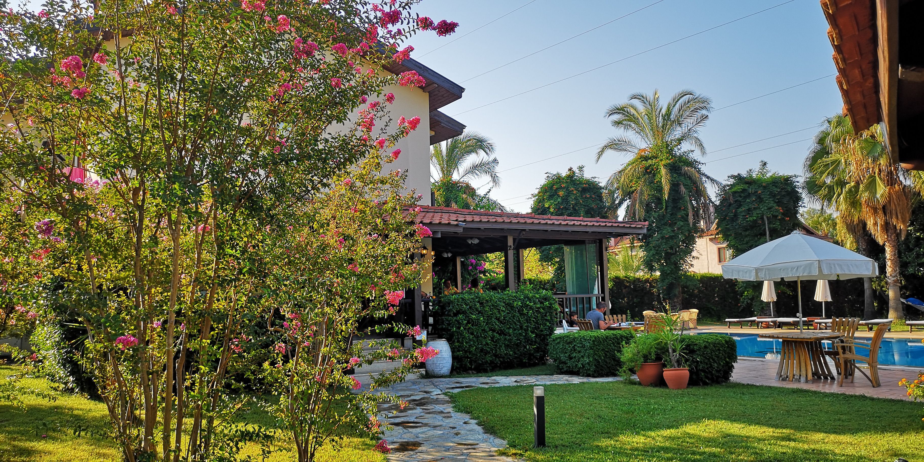 A pool area with a covered seating area and a garden with a pathway.