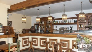 A bar area with wooden furniture, hanging chandeliers, and a variety of bottles on shelves. - San Marsial Benasque Hotel&Apartamentos (Benasque)