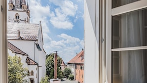 A window with a view of a church and buildings, a radiator below, and a partially open window blind. - Casa Luxemburg (Sibiu)