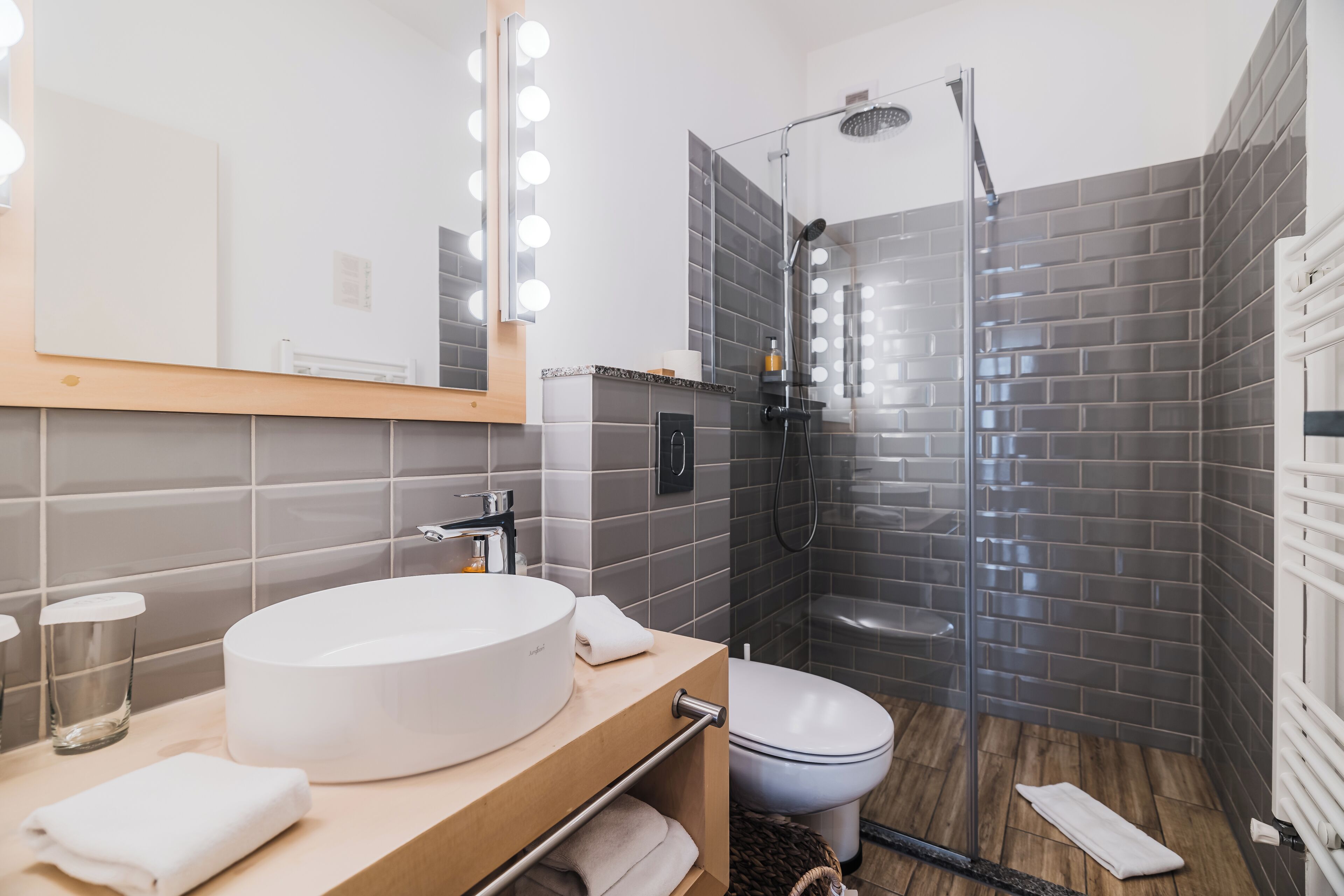 Ein modernes Badezimmer mit einem runden Waschbecken, einer Toilette und einer Duschkabine aus Glas.