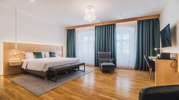 A modern hotel room with a bed, a desk, a chair, and a TV.