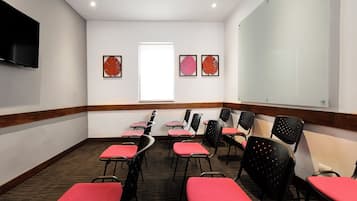 A conference room with a flat-screen TV, a whiteboard, and framed artwork on the walls.
