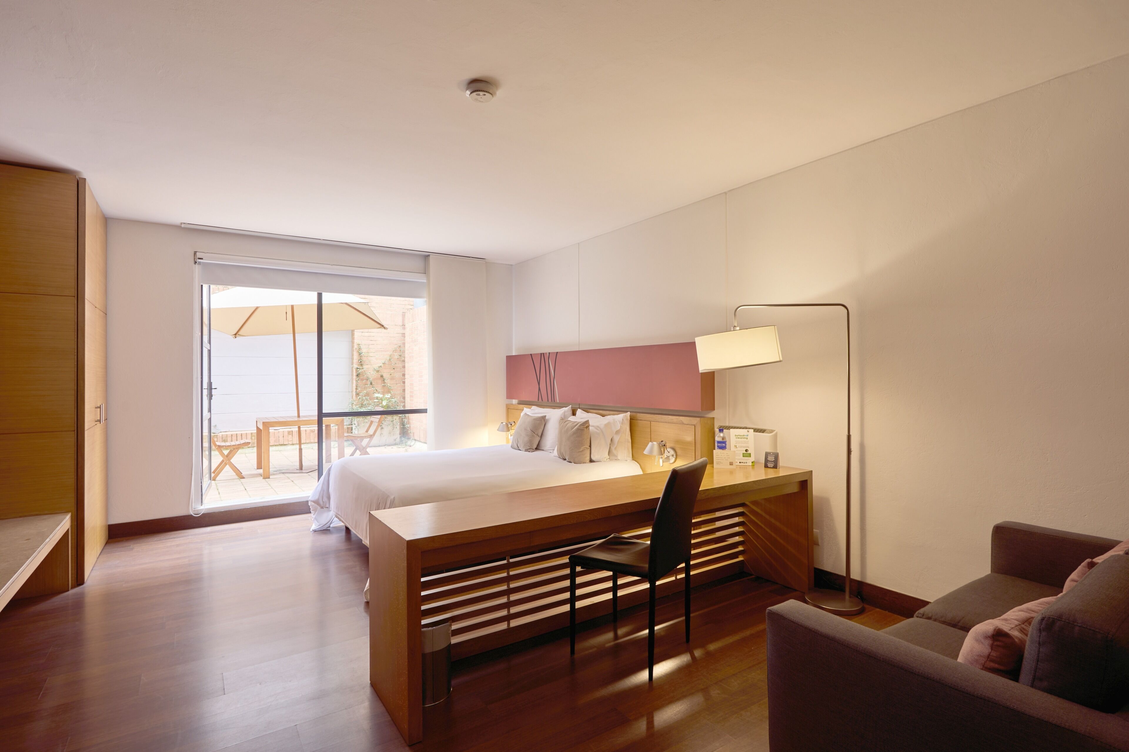 Quarto de hotel com cama, escrivaninha, cadeira e vista para o exterior.