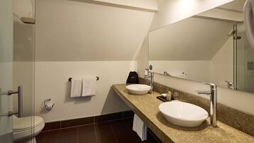 Une salle de bain moderne avec deux lavabos, des toilettes et une douche.