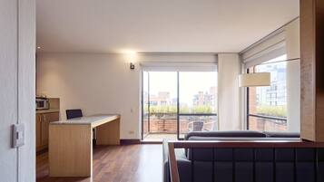 Un appartement moderne doté d’une kitchenette, d’un coin repas et d’un balcon offrant une vue sur la ville.
