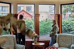 A room with large windows, a vase with flowers, and two chairs. - Bh la Quinta- Suites (Bogotá)
