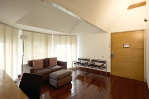 Una sala de estar moderna con un sofá, un reposapiés y un conjunto de sillas con estructura metálica.