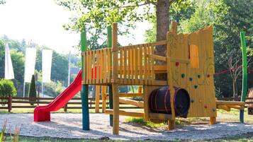 A playground with a slide, climbing wall, and a wooden structure with a barrel.
