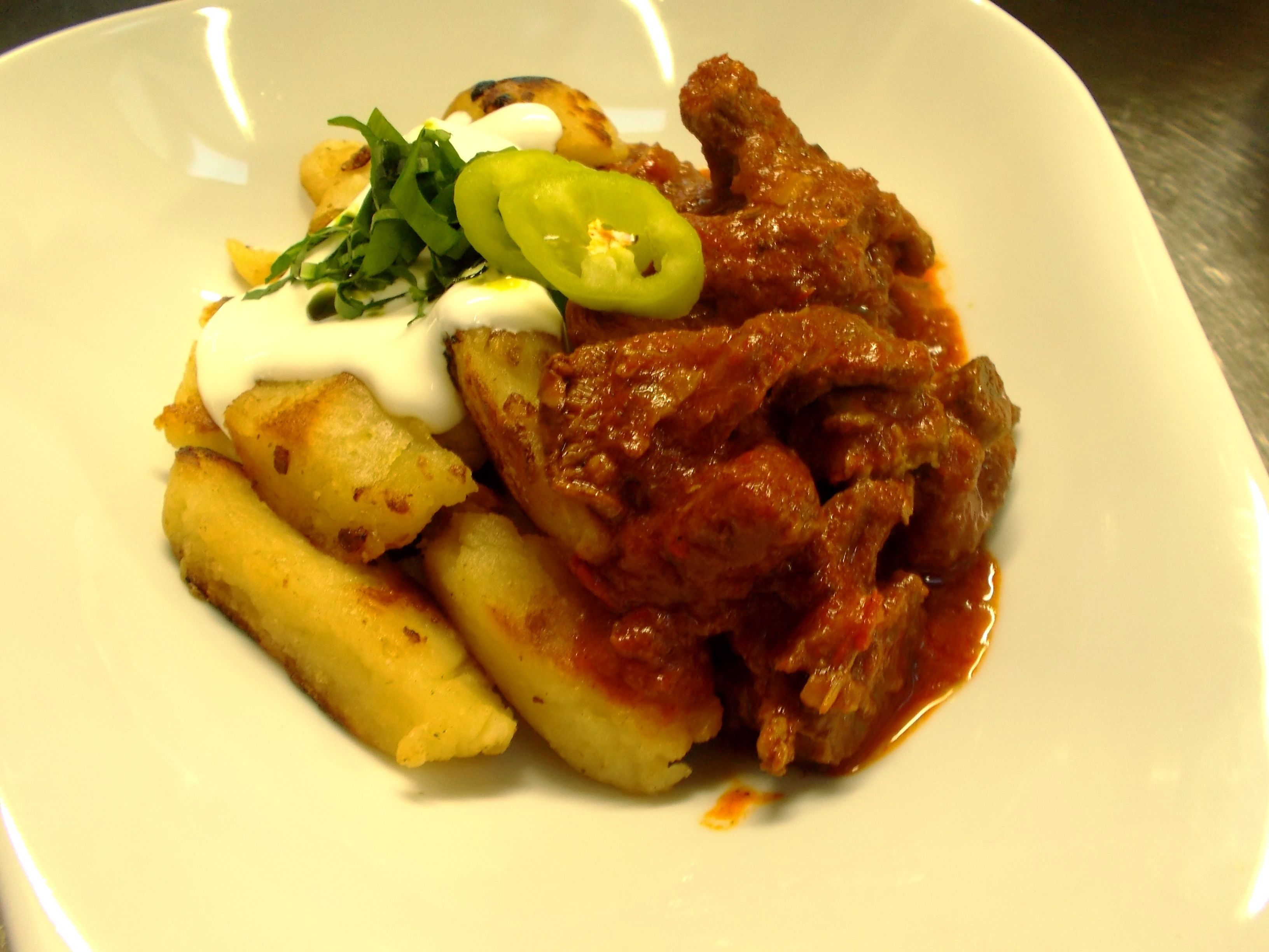 A plate with a meat dish, potatoes, and a dollop of sauce.