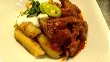 A plate with a meat dish, potatoes, and a dollop of sauce.