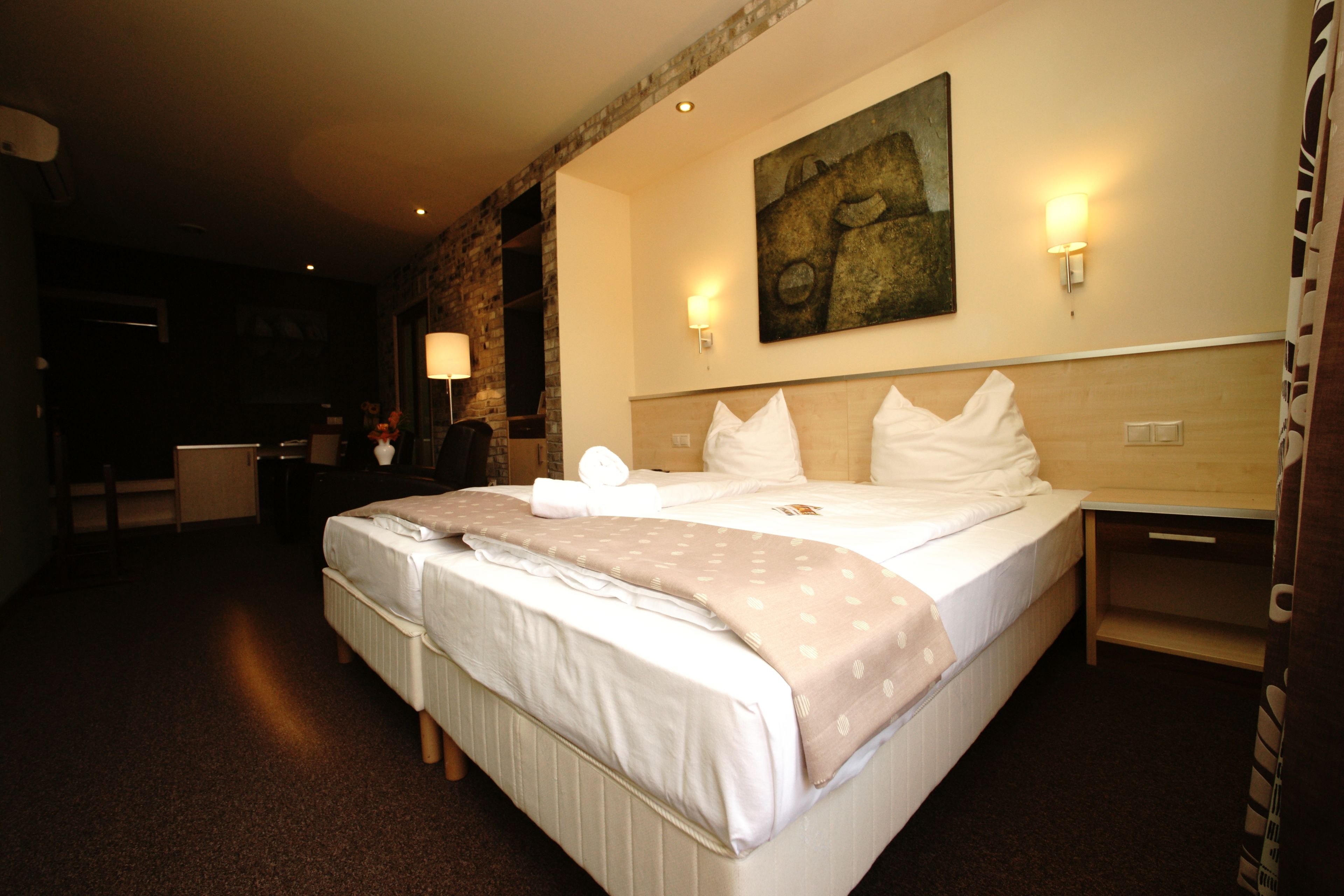 Una habitación de hotel con una cama grande, un escritorio, una lámpara y un cuadro en la pared.