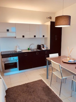 Una cucina moderna con forno integrato, lavello e zona pranzo con tavolo e sedie.
