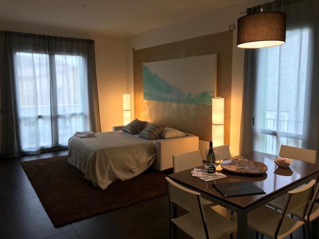 Ein Hotelzimmer mit Bett, Nachttisch, Lampe und einem Esstisch mit Stühlen.