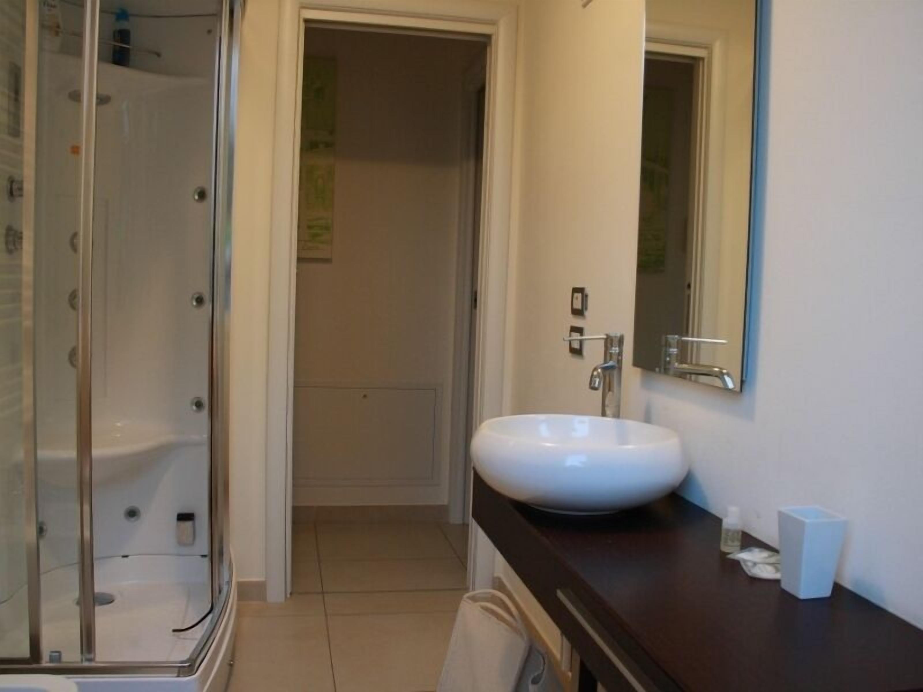 A bathroom with a glass-enclosed shower, a white sink, and a dark countertop.