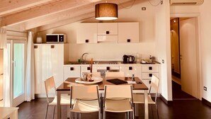A modern kitchen with wooden beams, a dining area with a table and chairs, and a view of the outside. - Resort del Lago (Desenzano del Garda)