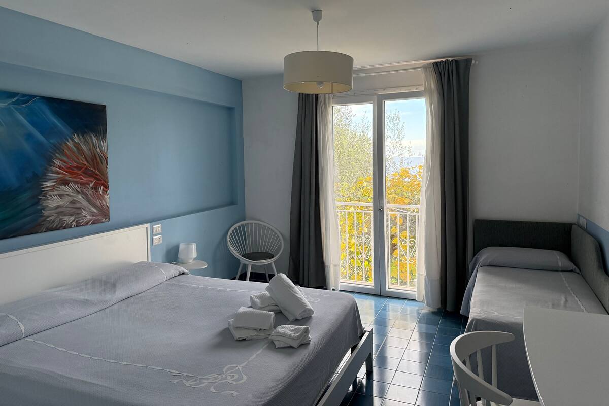Ein Hotelzimmer mit Bett, Stuhl, Tisch und einem Bild an der Wand.