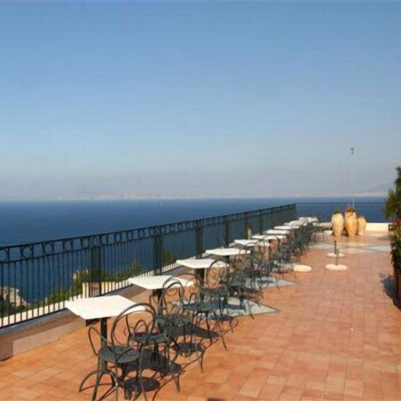 A terrace with outdoor seating and a view of the sea.