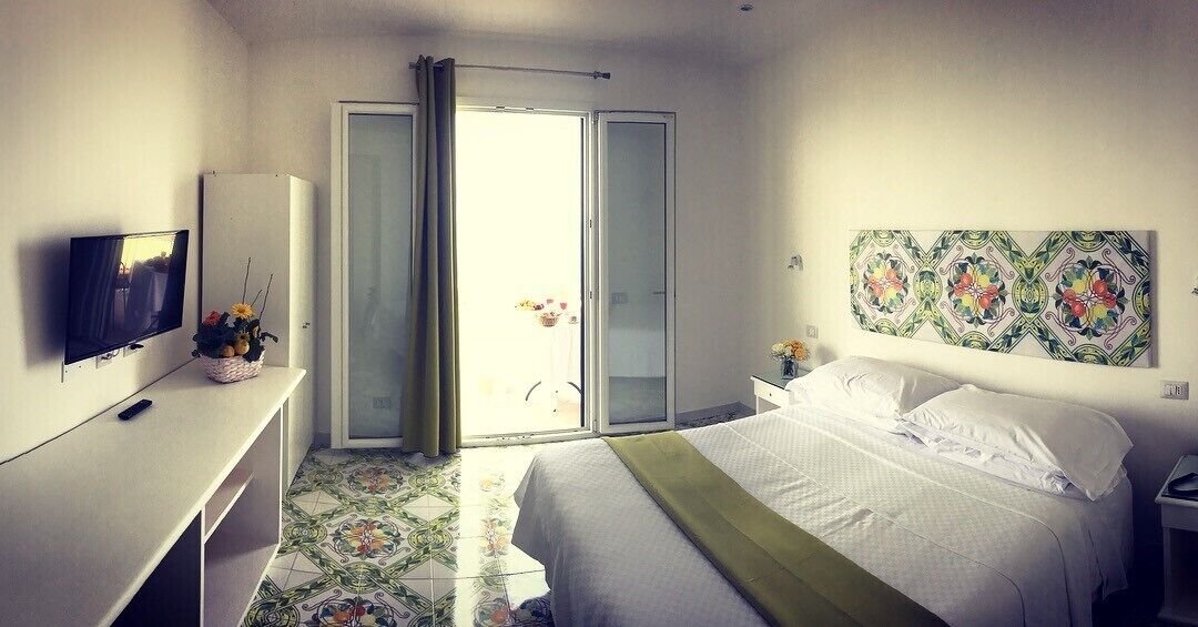 Habitación de hotel con cama, televisión, escritorio, silla, ventana y puerta.