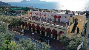 A building with a terrace, outdoor seating, and a view of the sea. - Hotel Villa Pina Antico Francischiello (Massa Lubrense)