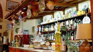 A bar area with a counter, stools, and shelves stocked with bottles. - Hotel Villa Pina Antico Francischiello (Massa Lubrense)