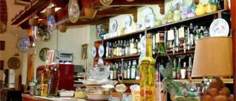 A bar area with a counter, stools, and shelves stocked with bottles.