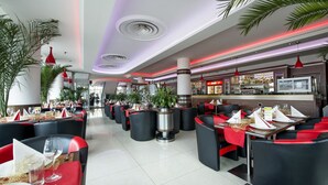 A modern restaurant with black and red seating, a bar area, and ambient lighting. - Alessandria (Hradec Kralove)