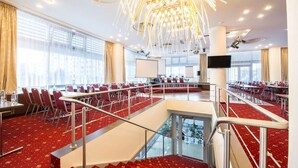 A conference room with red carpeted floors, multiple tables, and chairs. - Alessandria (Hradec Kralove)
