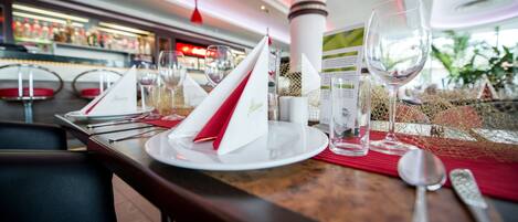 Un ambiente de restaurante con una mesa dispuesta para comer, incluyendo platos, vasos y cubiertos.
