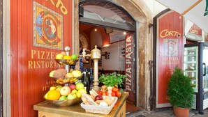 A wooden counter with a fruit display and a potted plant. - Pension Corto (Prague)