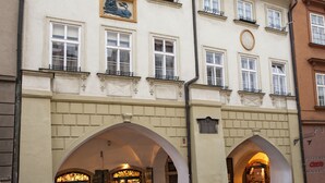 A building with multiple windows, a lion sculpture, and an archway entrance. - Pension Corto (Prague)