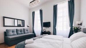 A hotel room with a large bed, a sofa, a TV, and a mirror. - Pension Corto (Prague)