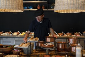 Un chef préparant des plats dans une cuisine équipée de casseroles en cuivre et d’un buffet.