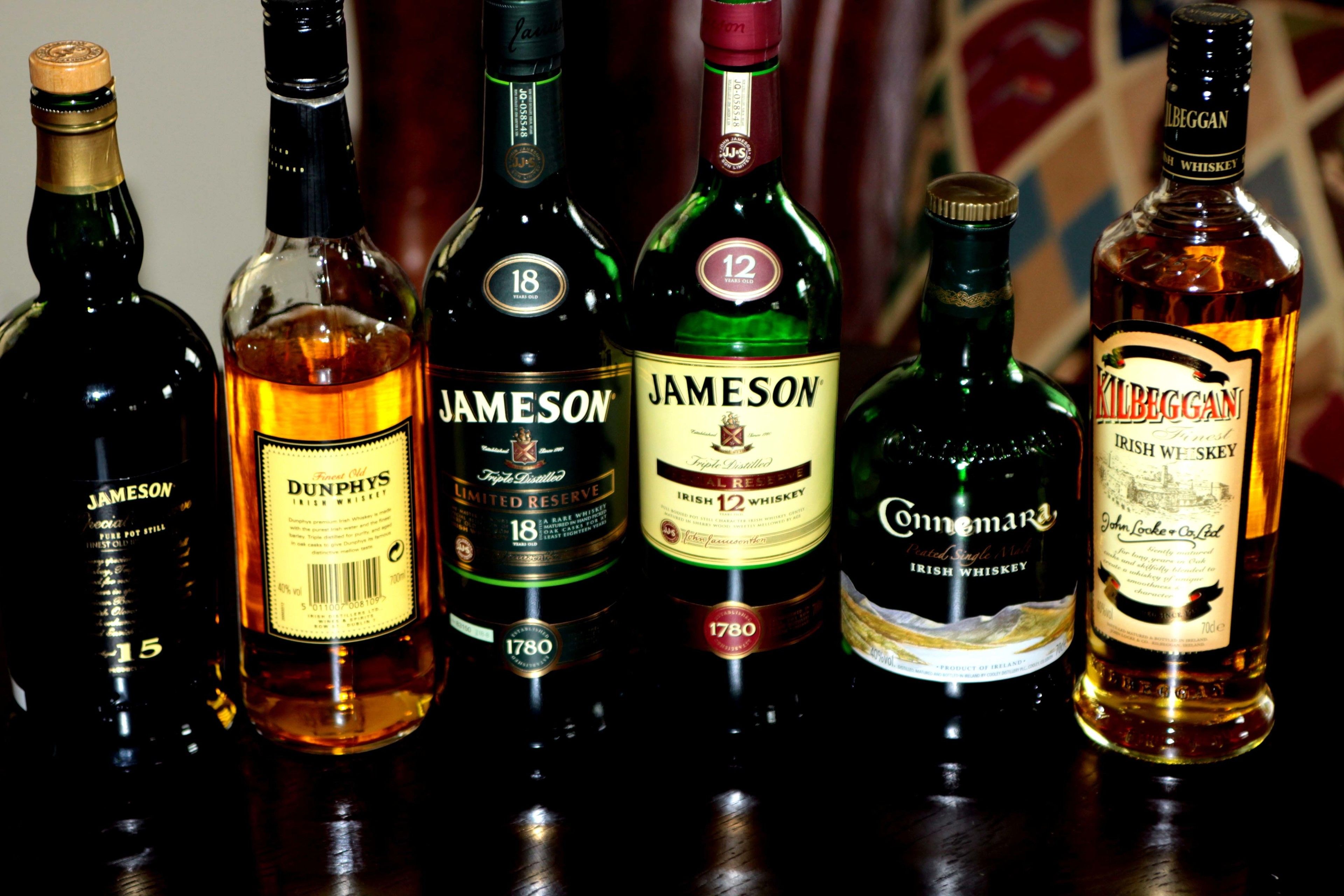 Varias botellas de whisky sobre una superficie reflectante.