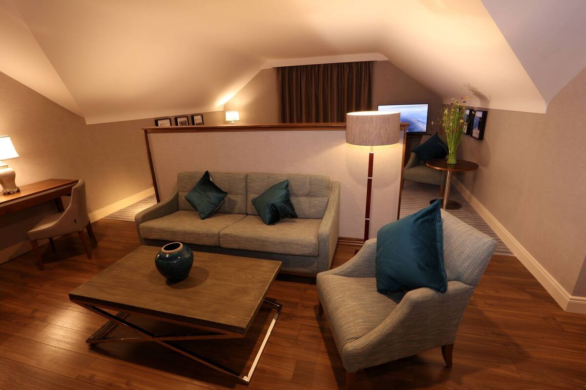 A cozy living room with a sofa, armchair, coffee table, and a lamp.