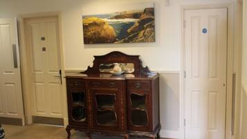 A room with a wooden cabinet, a painting of a coastal landscape, and white doors.