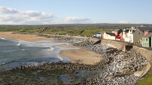 Uma cidade costeira com uma praia de areia, costa rochosa e edifícios ao longo do muro marítimo.