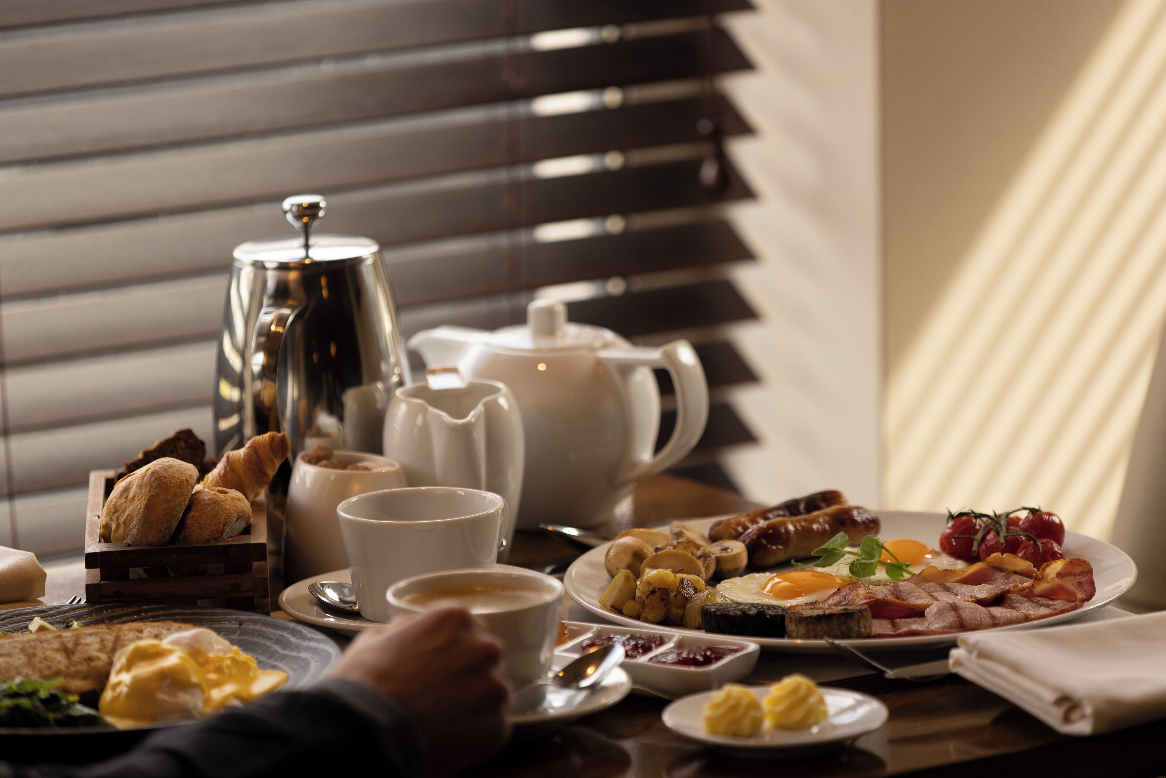 Una mesa de desayuno con diferentes alimentos, una taza de café y una tetera.