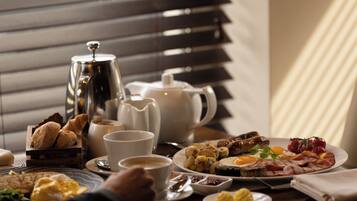 Una mesa de desayuno con diferentes alimentos, una taza de café y una tetera.