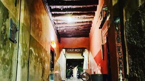 A narrow alleyway with a rustic, weathered appearance, leading to a shop named "DAR MOKI."
