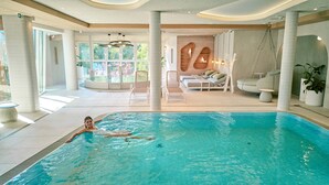 Piscina con sillones de descanso y una zona de estar con vistas a zonas verdes.