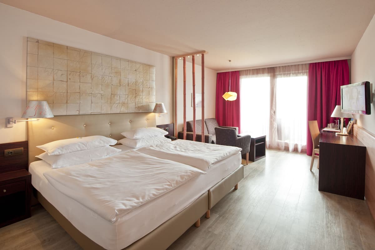 Una habitación de hotel con una cama grande, un escritorio, una silla y un televisor.