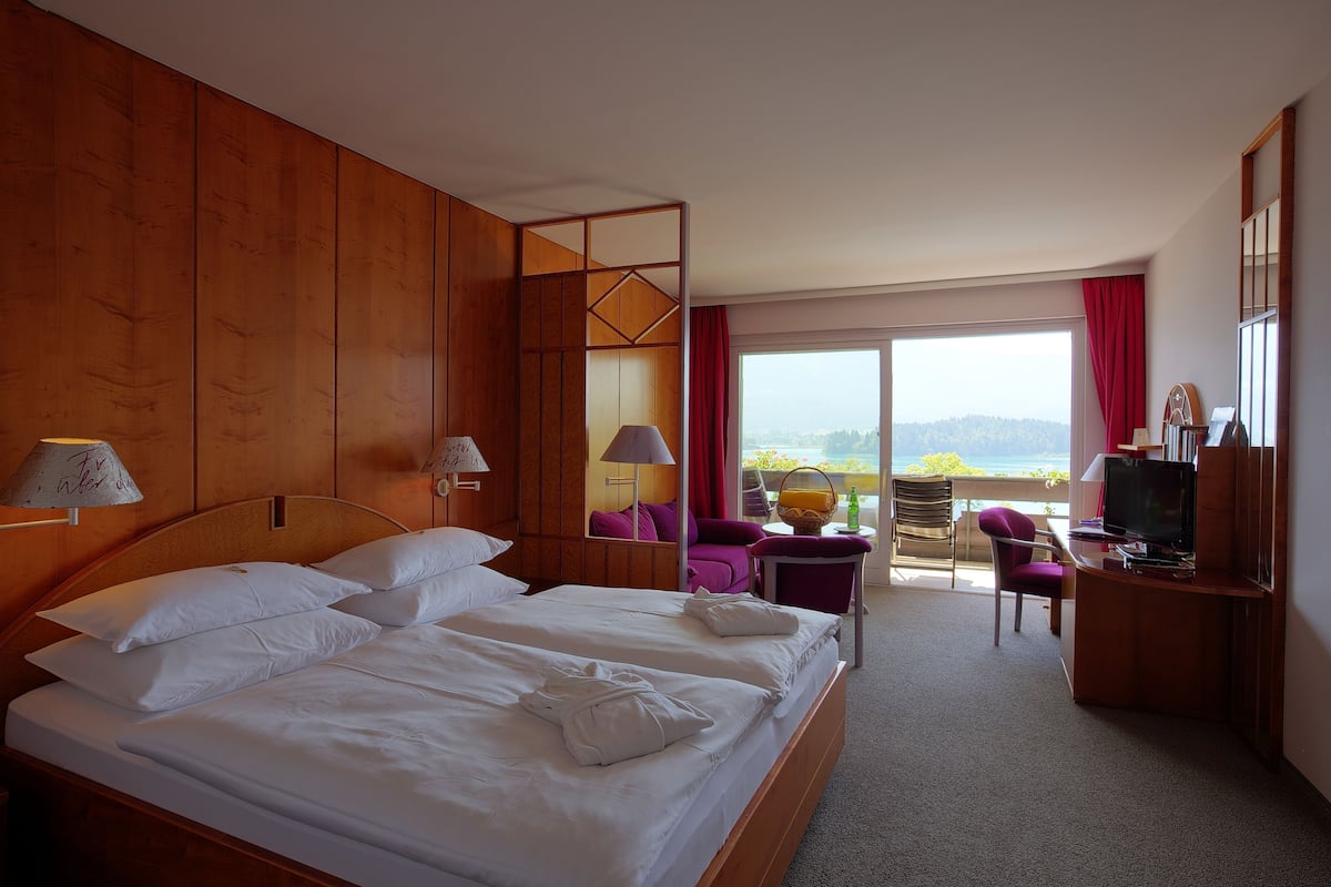 Una habitación de hotel con una cama grande, un escritorio con televisor y un balcón con vistas.