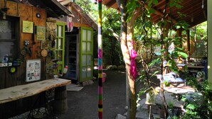 A rustic wooden building with a green door, a wooden table, and a hanging bell. - Daphne House (Kumluca)