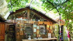 A rustic wooden structure with a wooden table and benches, surrounded by greenery. - Daphne House (Kumluca)
