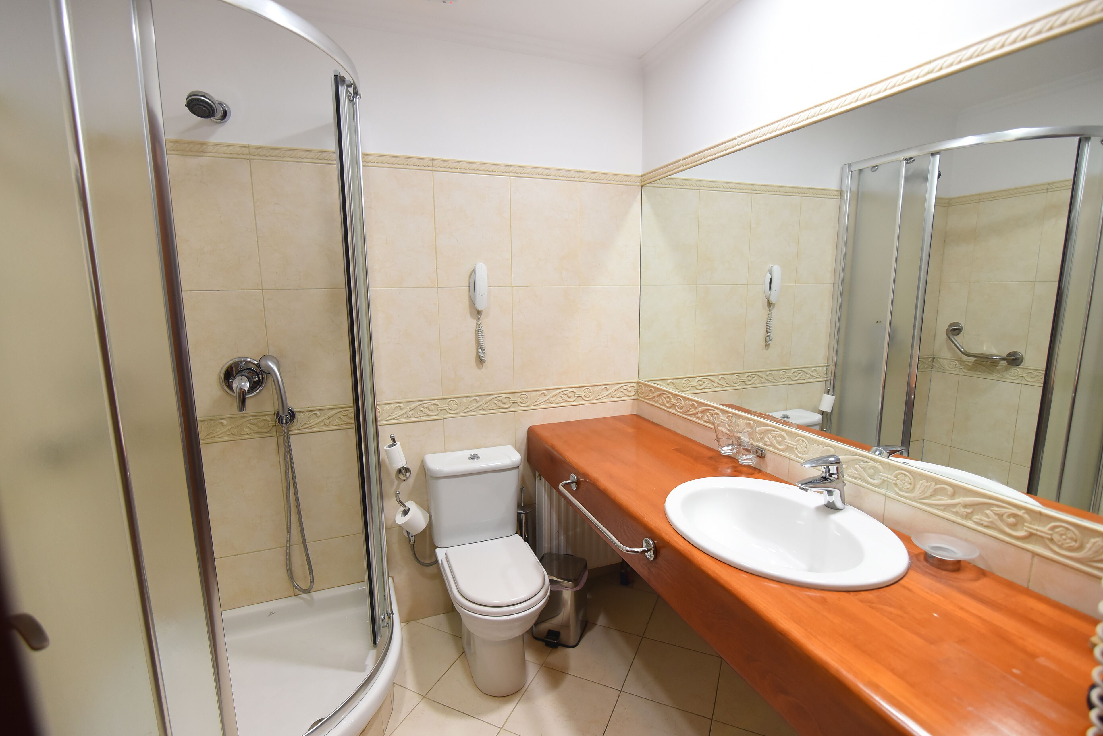 Ein Badezimmer mit Dusche, Toilette, Waschbecken und einem großen Spiegel.