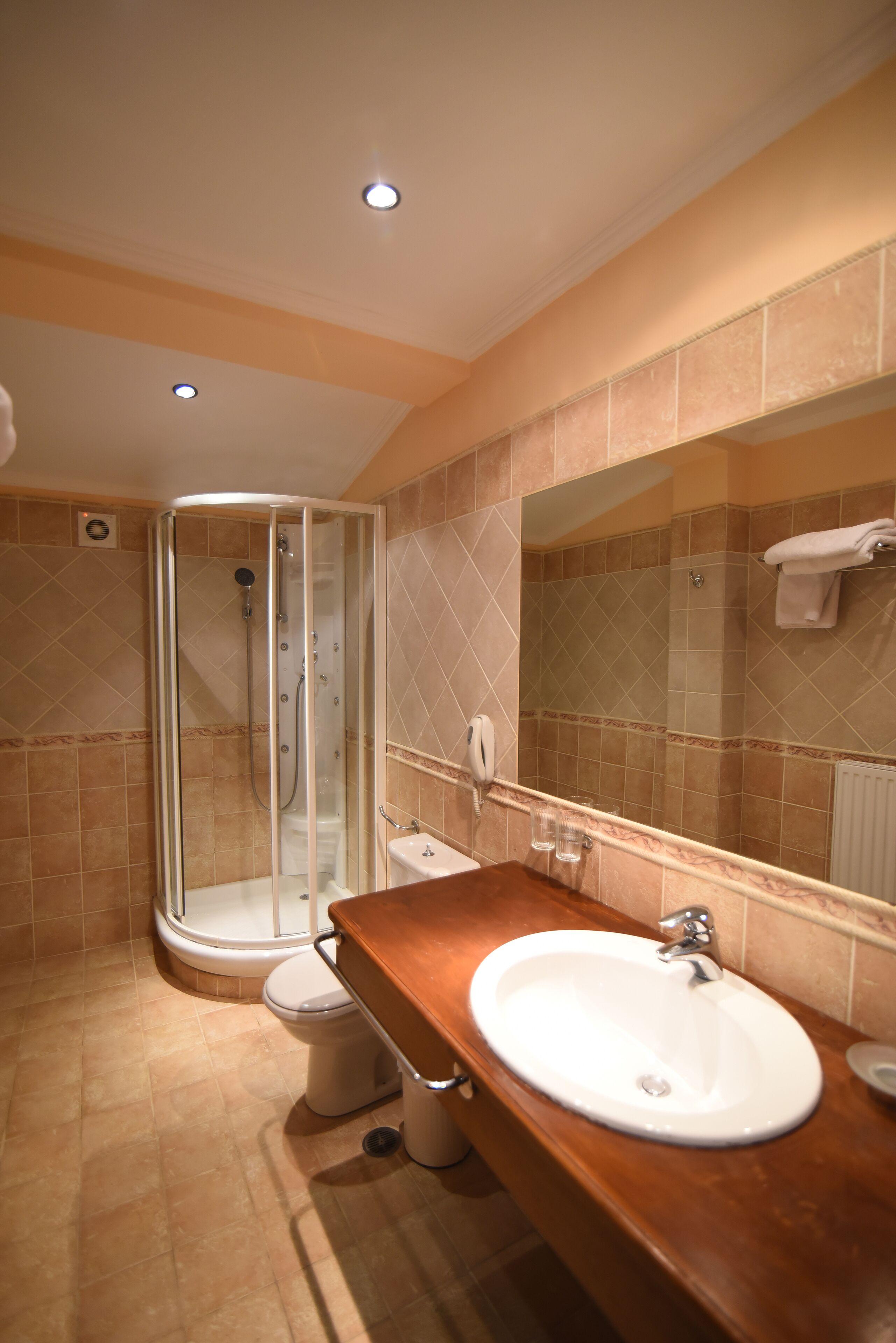 A bathroom with a glass-enclosed shower, a white sink, and a mirror.